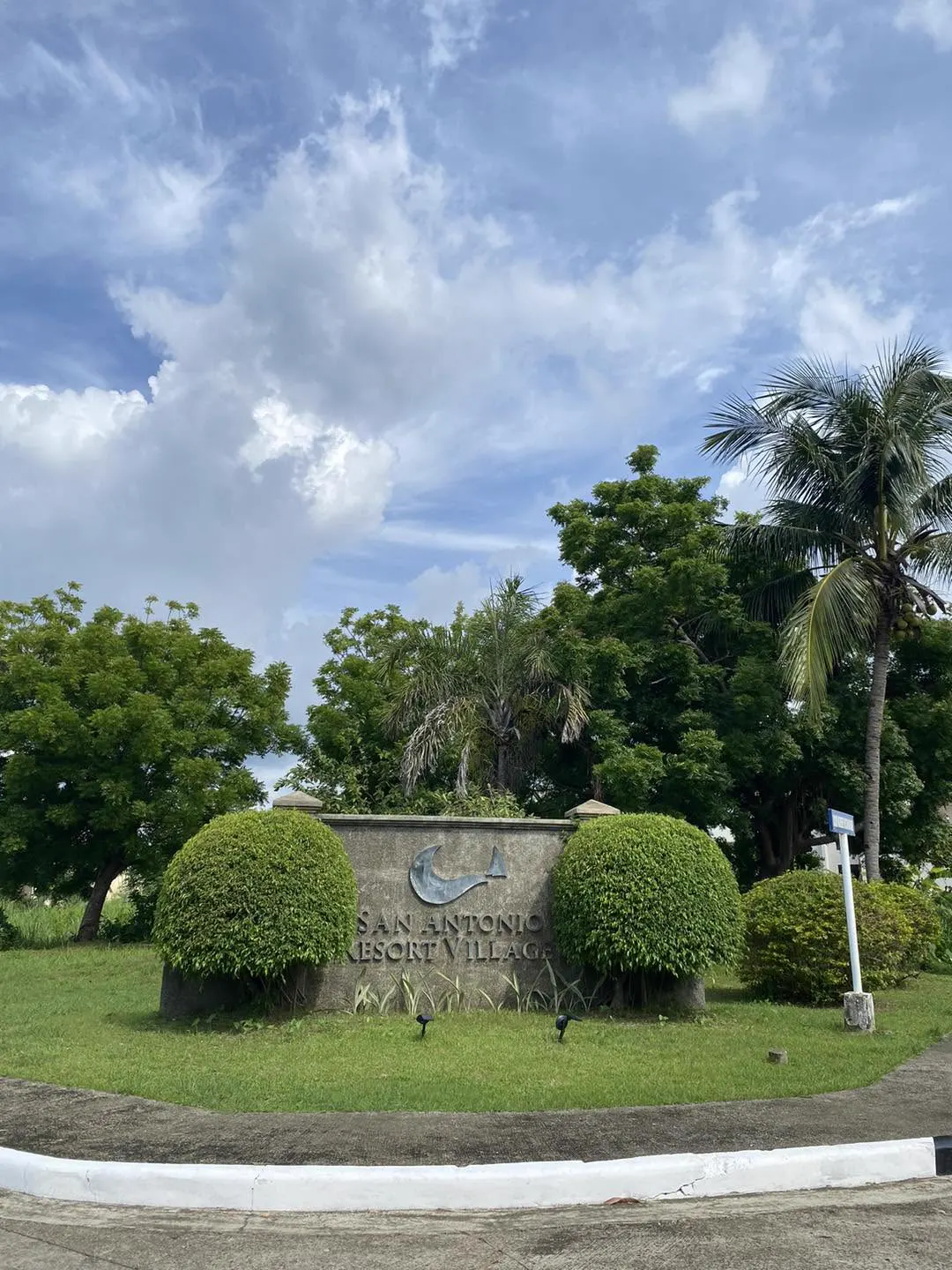 San Antonio Resort Village entrance marker set among trimmed shrubs and palms