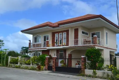Two storey house with a red tiled roof, brick trim, balconies and a metal perimeter fence