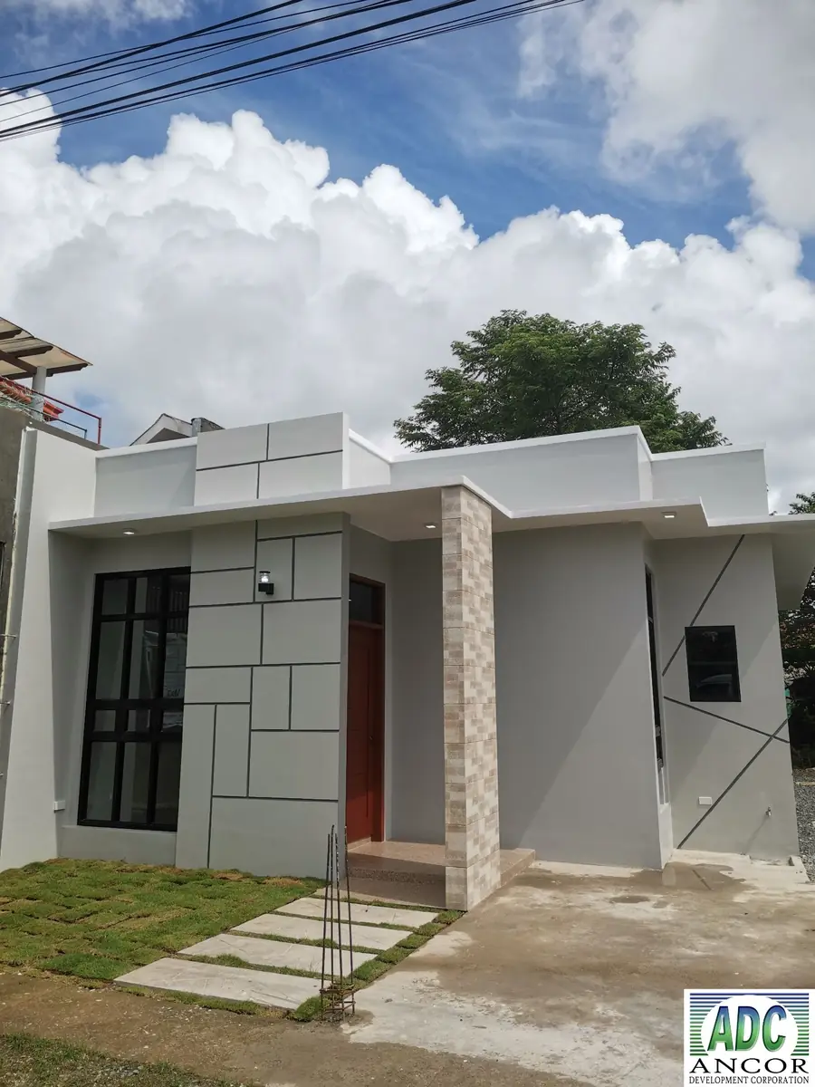 Angled front view showing red front door under the porch, stone clad column, and concrete driveway