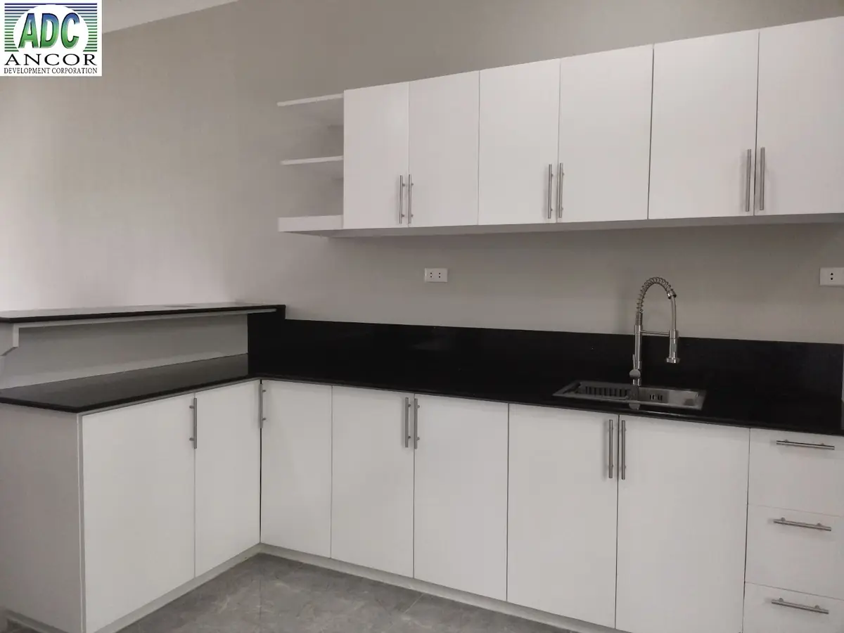 L shaped kitchen with white cabinets, black granite counter and backsplash, and a stainless sink