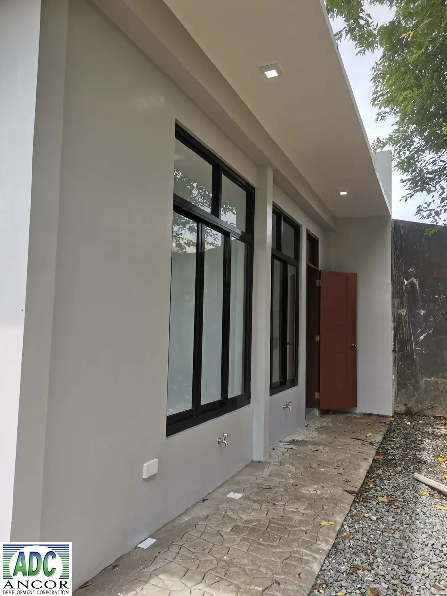 Side passage with stone pattern paving, tall windows, faucets, and an open wooden back door