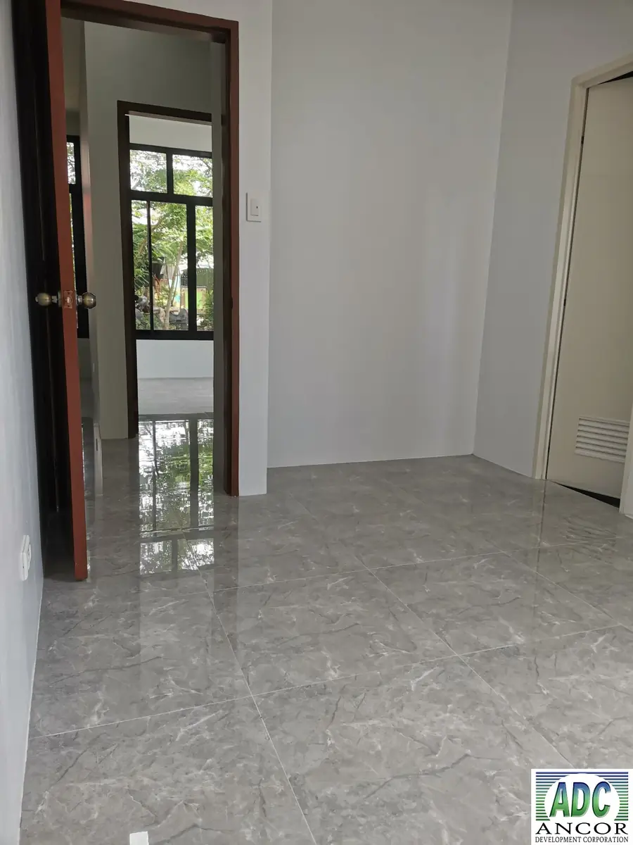 Empty room with an open wood framed door to another room and grey marble look floor tile