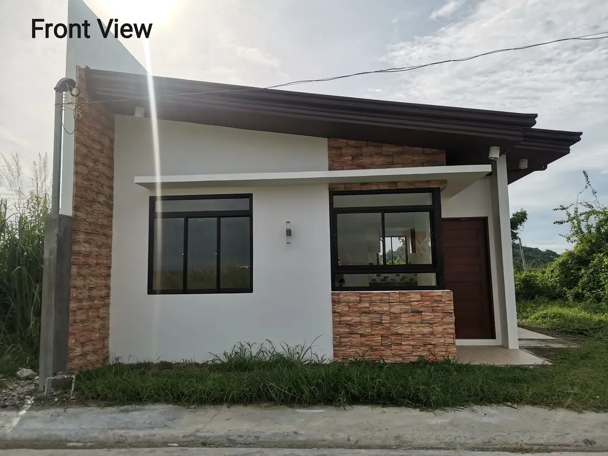 Front view of a white bungalow with stone clad panels, sliding windows, and wood front door