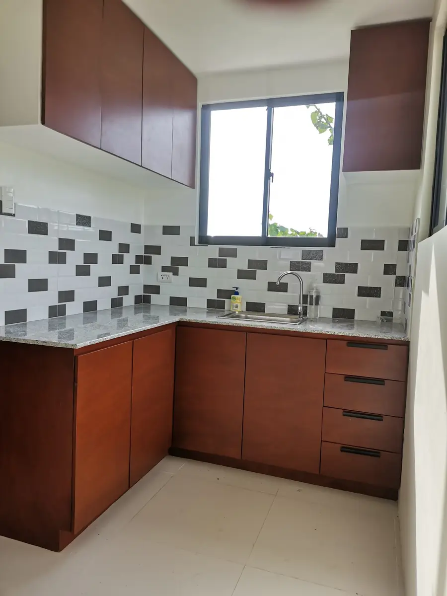 Kitchen with cherry wood cabinets, granite counter, brick tile backsplash, and a window over the sink