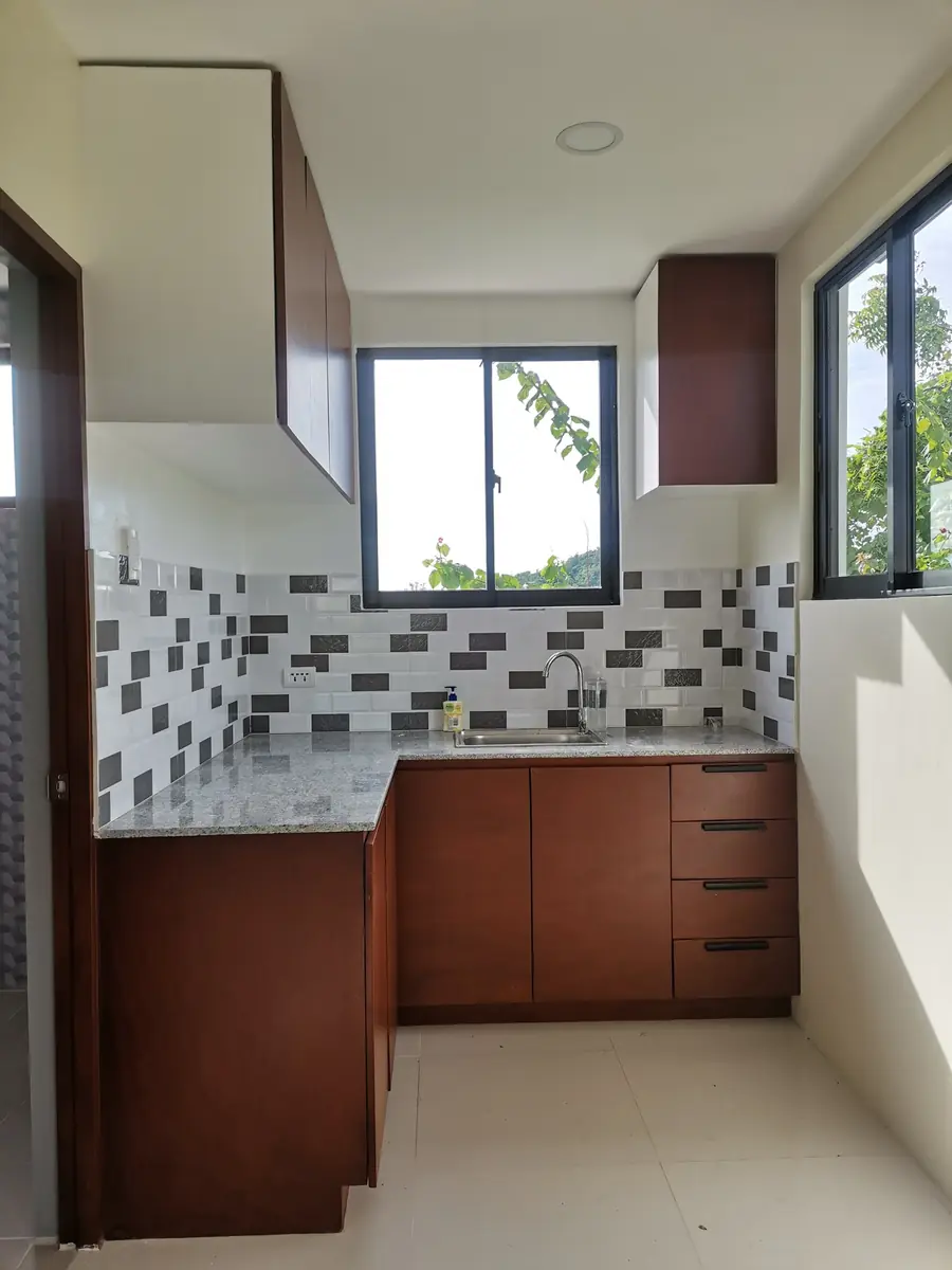 Kitchen corner with cherry wood cabinets, granite counter, brick tile backsplash, and two windows