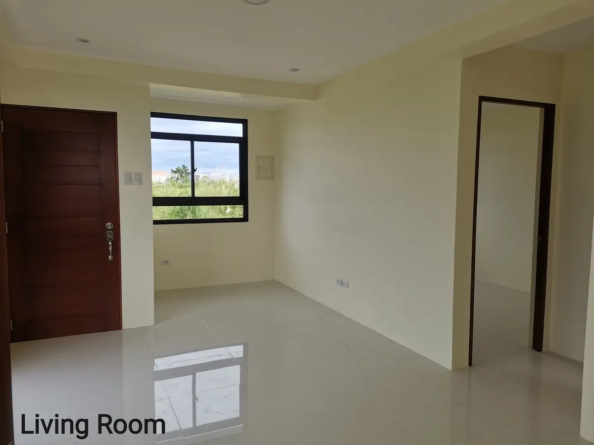 Living room with wood front door, black framed window, cream walls, and glossy white tile floor