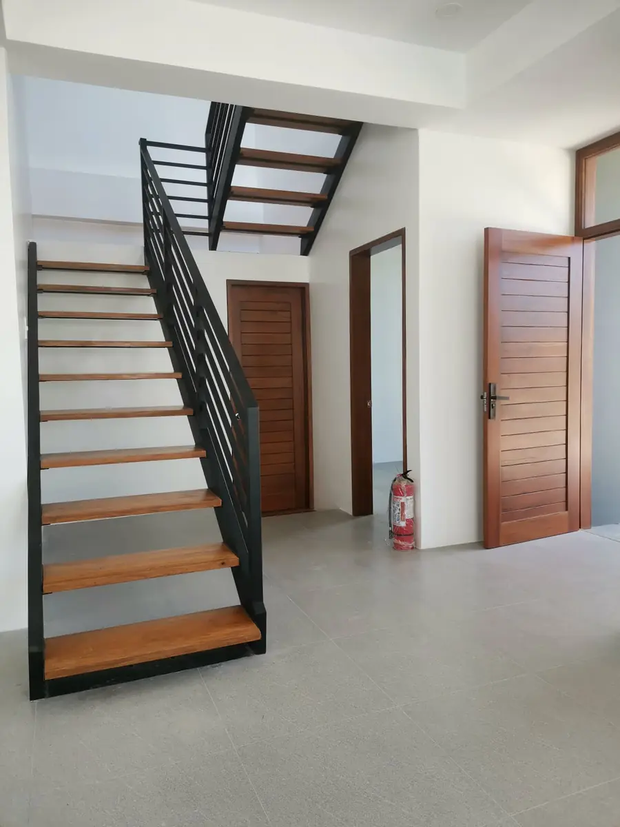 Interior with an open riser staircase, wood treads and black steel railing, and wood doors