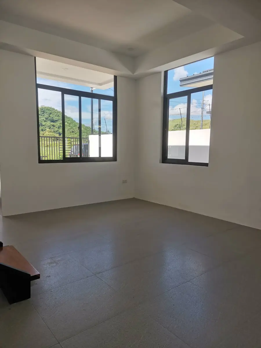 Empty upper room with two black framed windows looking onto hills, white walls, and grey tile floor