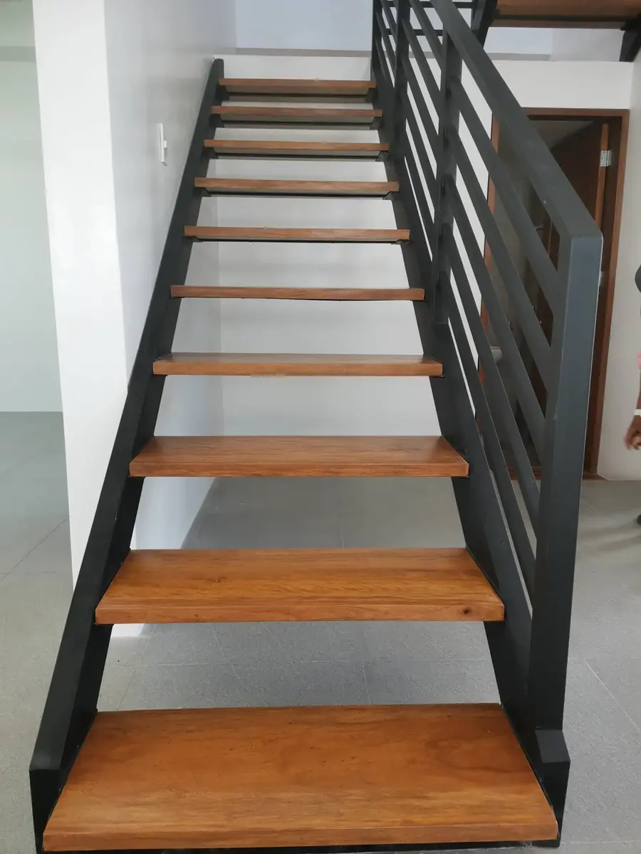 Open riser staircase with wood treads and black steel stringer and railing, wood door at the landing
