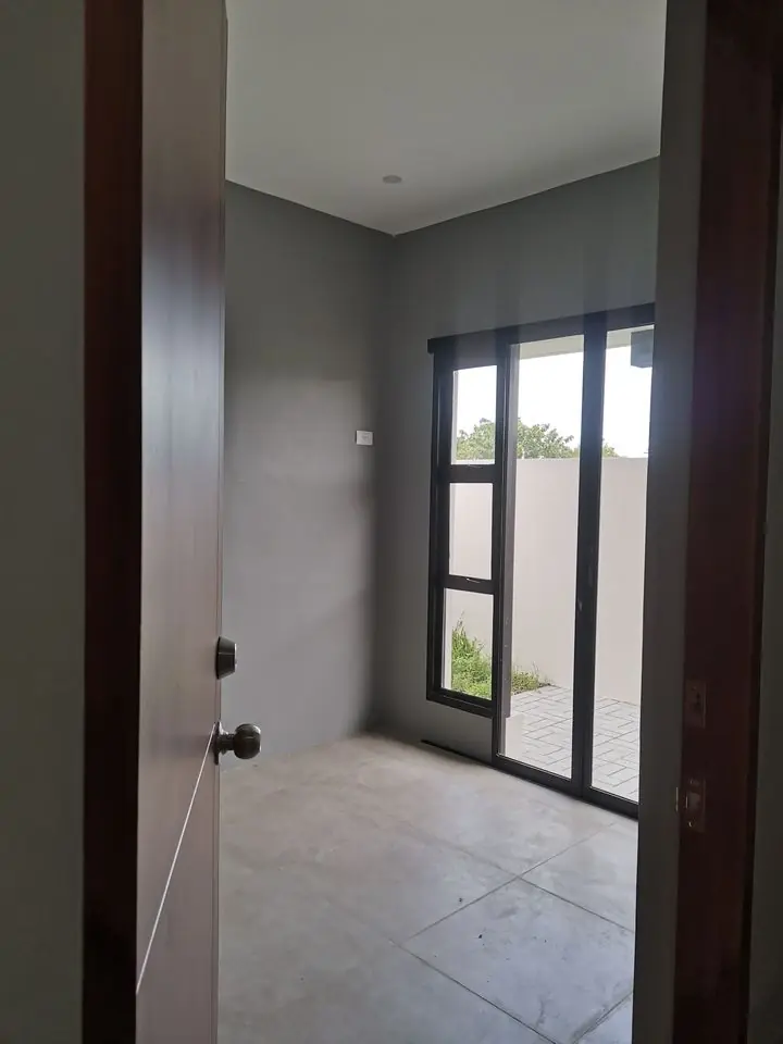 Empty room with grey walls and a black framed glass door leading to a paved side yard