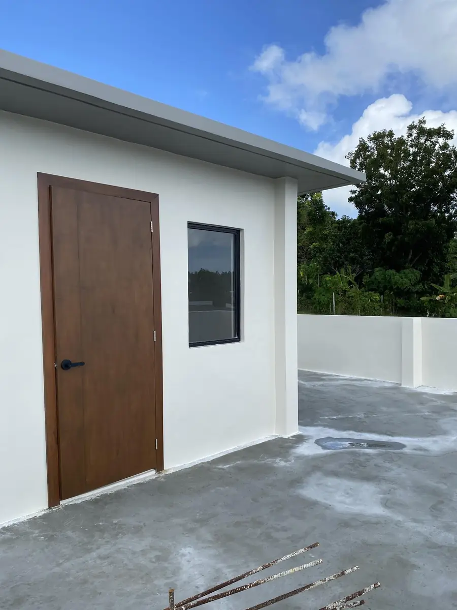 Roof deck with a concrete floor, white walls, a wood door, and a black framed window