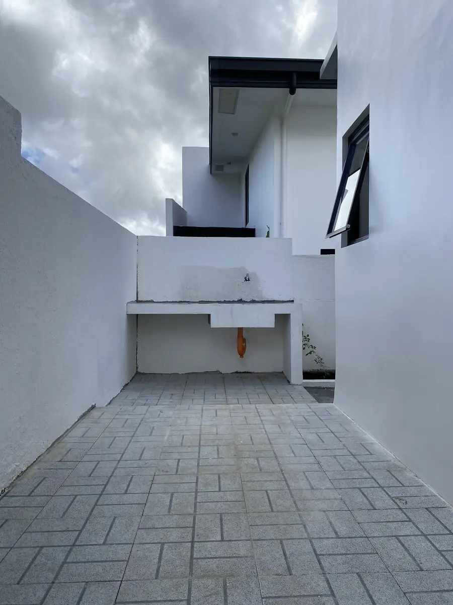 Paved service yard with a concrete laundry counter and faucet between white walls