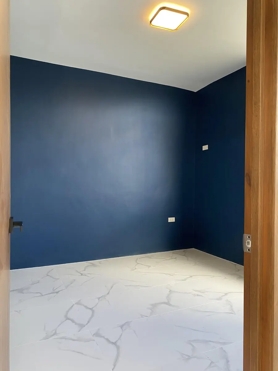 Empty bedroom with navy blue walls, marble look tile floor, and a square ceiling light