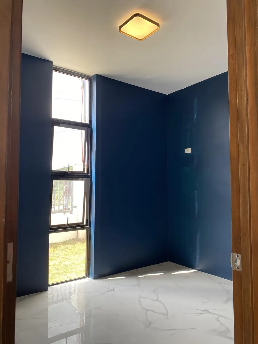 Empty bedroom with navy blue walls, a tall window, marble look tile floor, and a square ceiling light