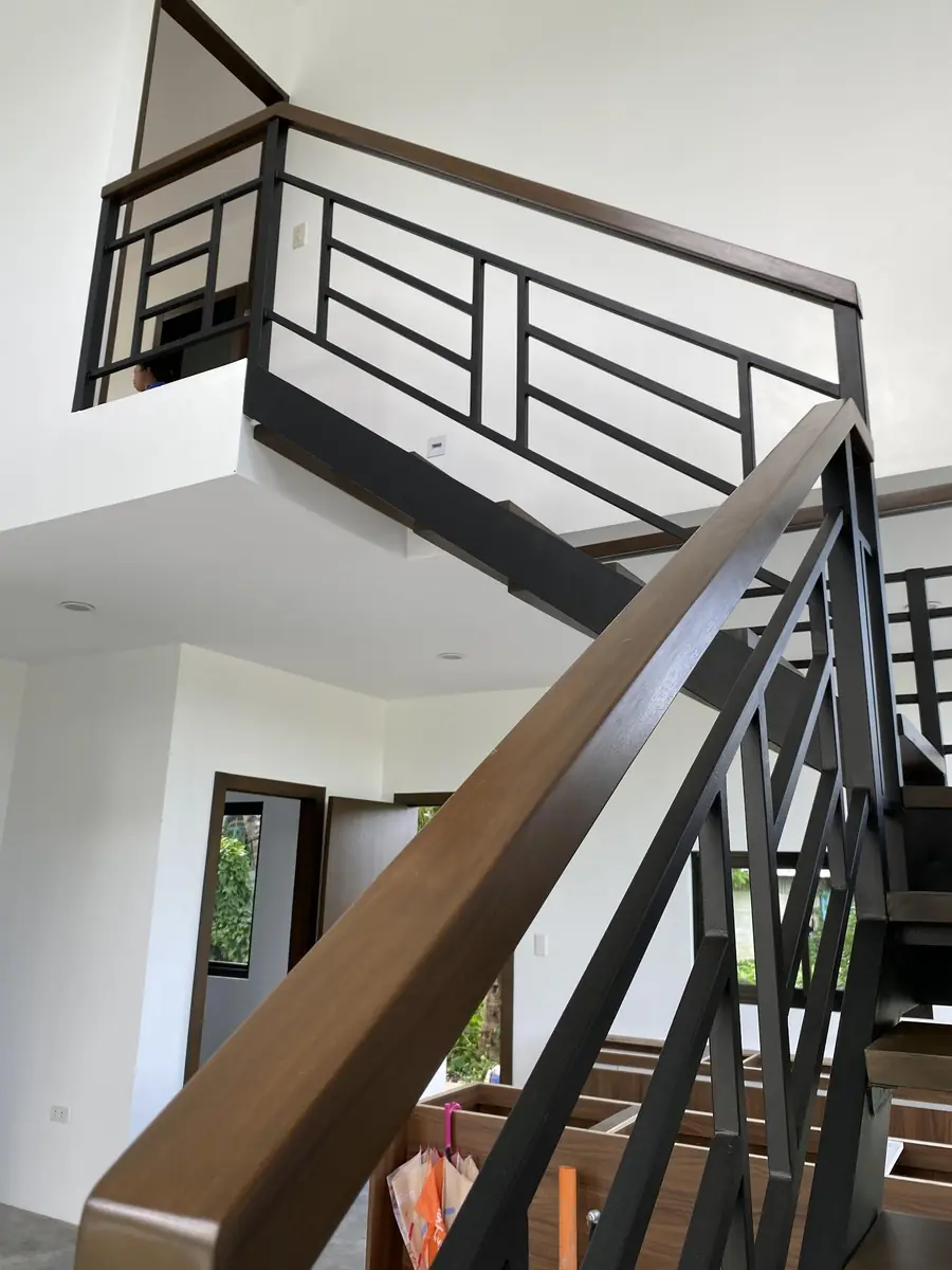 Staircase and second floor landing with wood handrails and black steel railings