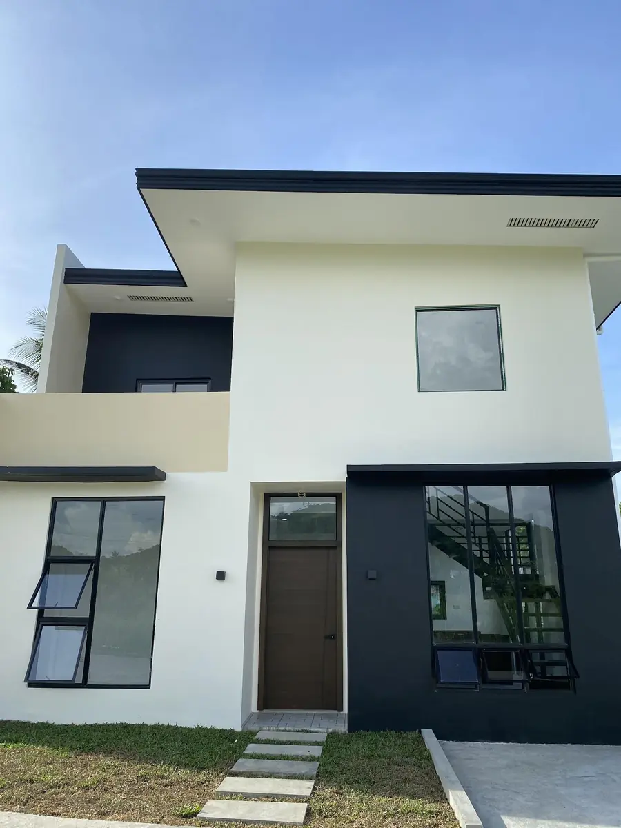Front of a two storey house with balcony, wood door, awning windows, and stairs visible through the glass