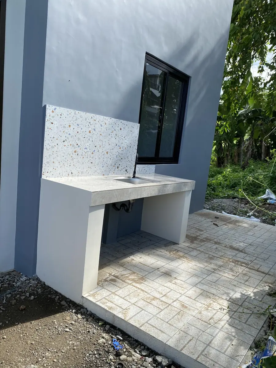 Outdoor dirty kitchen counter with sink, terrazzo look backsplash, and a black framed window