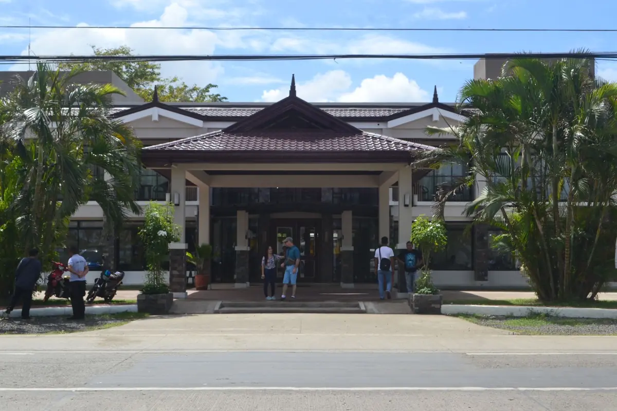 Two storey clubhouse building with a tiled pavilion roof and palm trees at the entrance